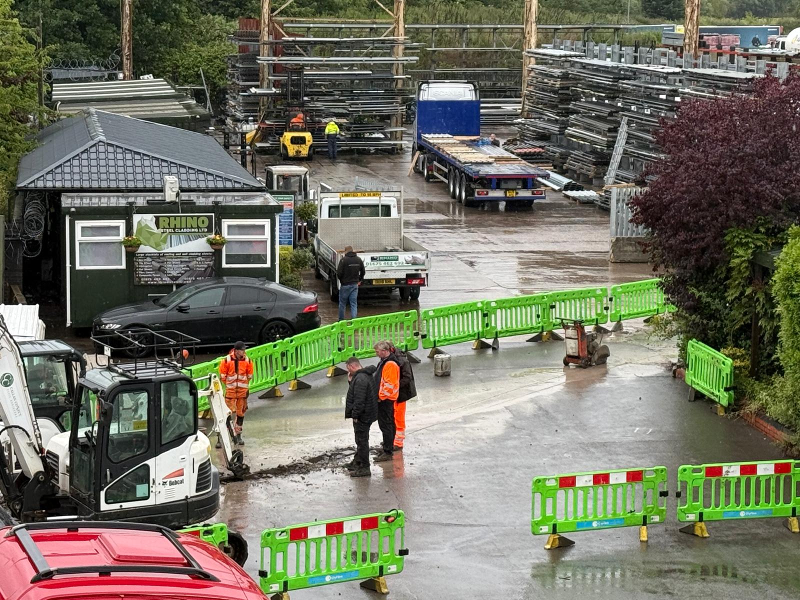 Roadwork contractors study the aftermath of their power cable blunder at the Cedars industrial estate